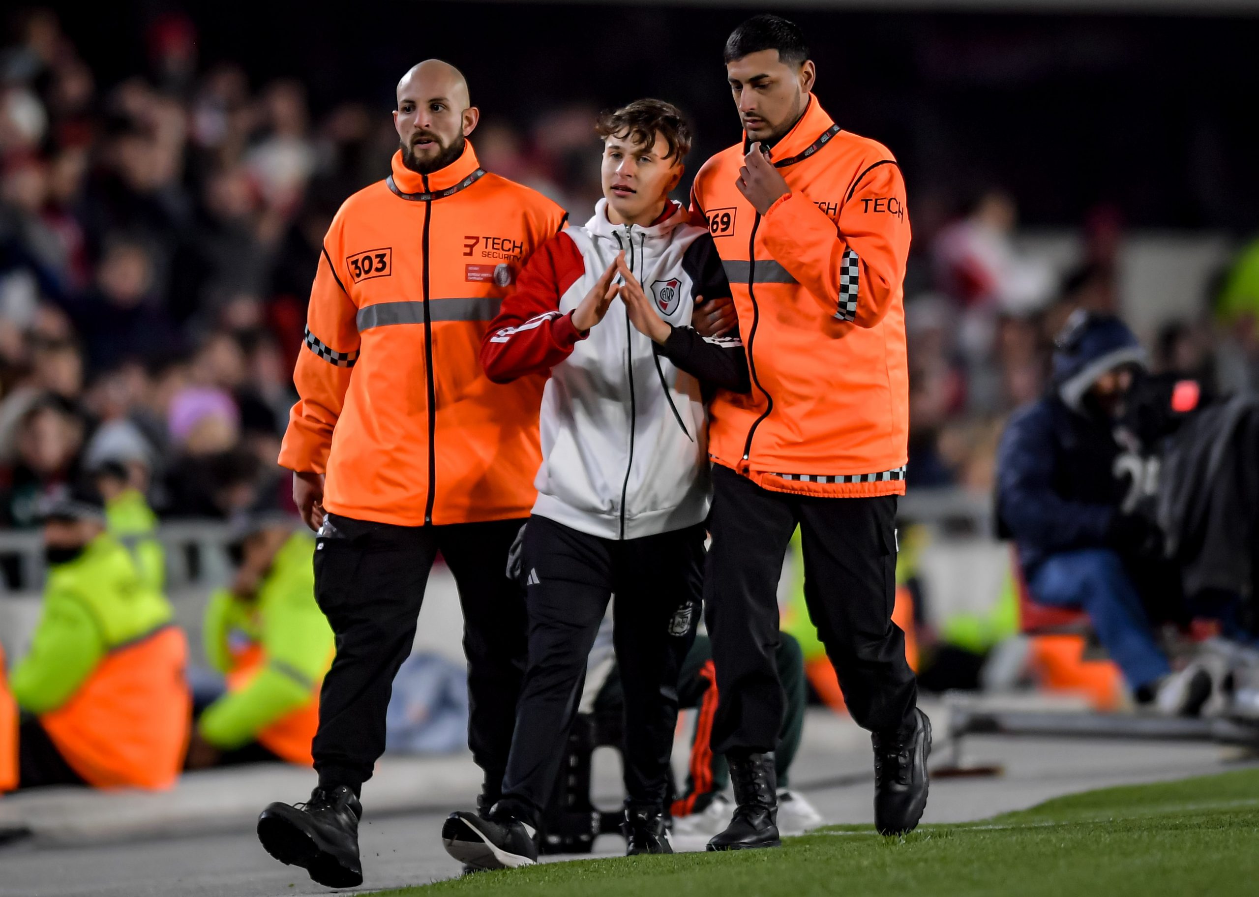 BUENOS AIRES, ARGENTINA - MAY 18: A pitch invader of River Plate is escorted out by security employees during a match between River Plate and Belgrano as part of Liga Profesional 2024 at Estadio Mas Monumental Antonio Vespucio Liberti on May 18, 2024 in Buenos Aires, Argentina. (Photo by Marcelo Endelli/Getty Images)